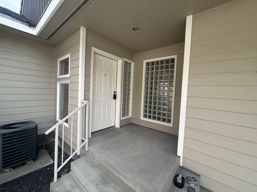 Exterior of a home entry with a white door, glass block window, and concrete steps.