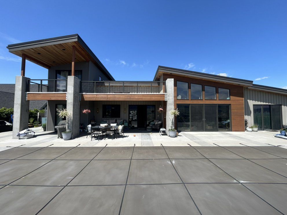 Modern house with patio, wooden accents, and a covered deck under a blue sky.