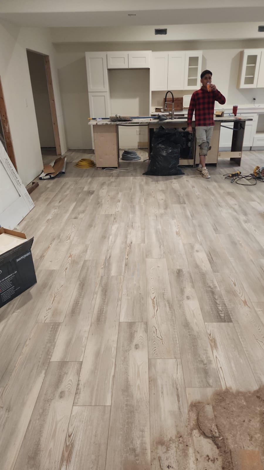 A man is standing in a kitchen talking on a cell phone.