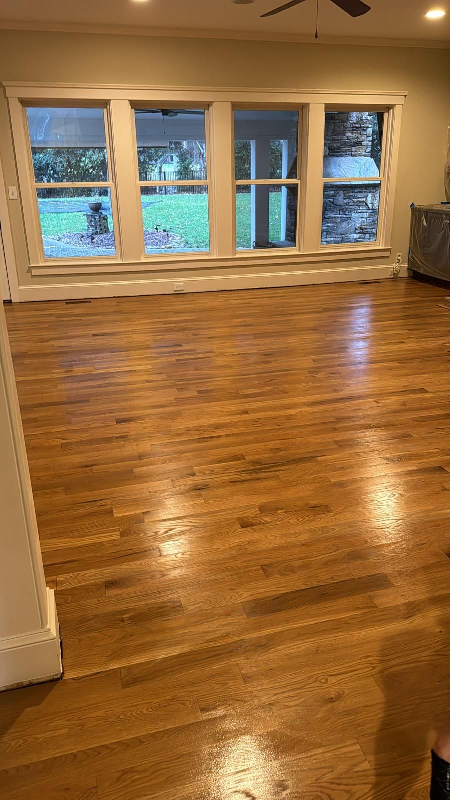 An empty living room with hardwood floors and a ceiling fan.