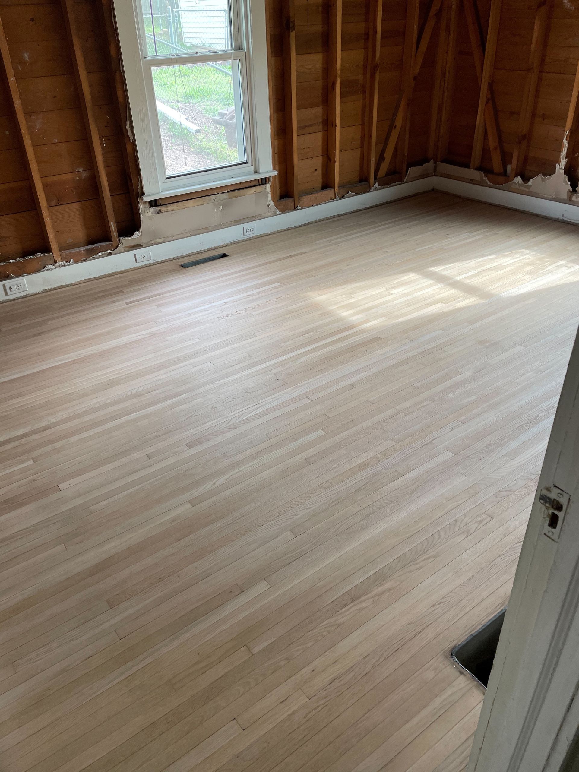 A room with a wooden floor and a window.