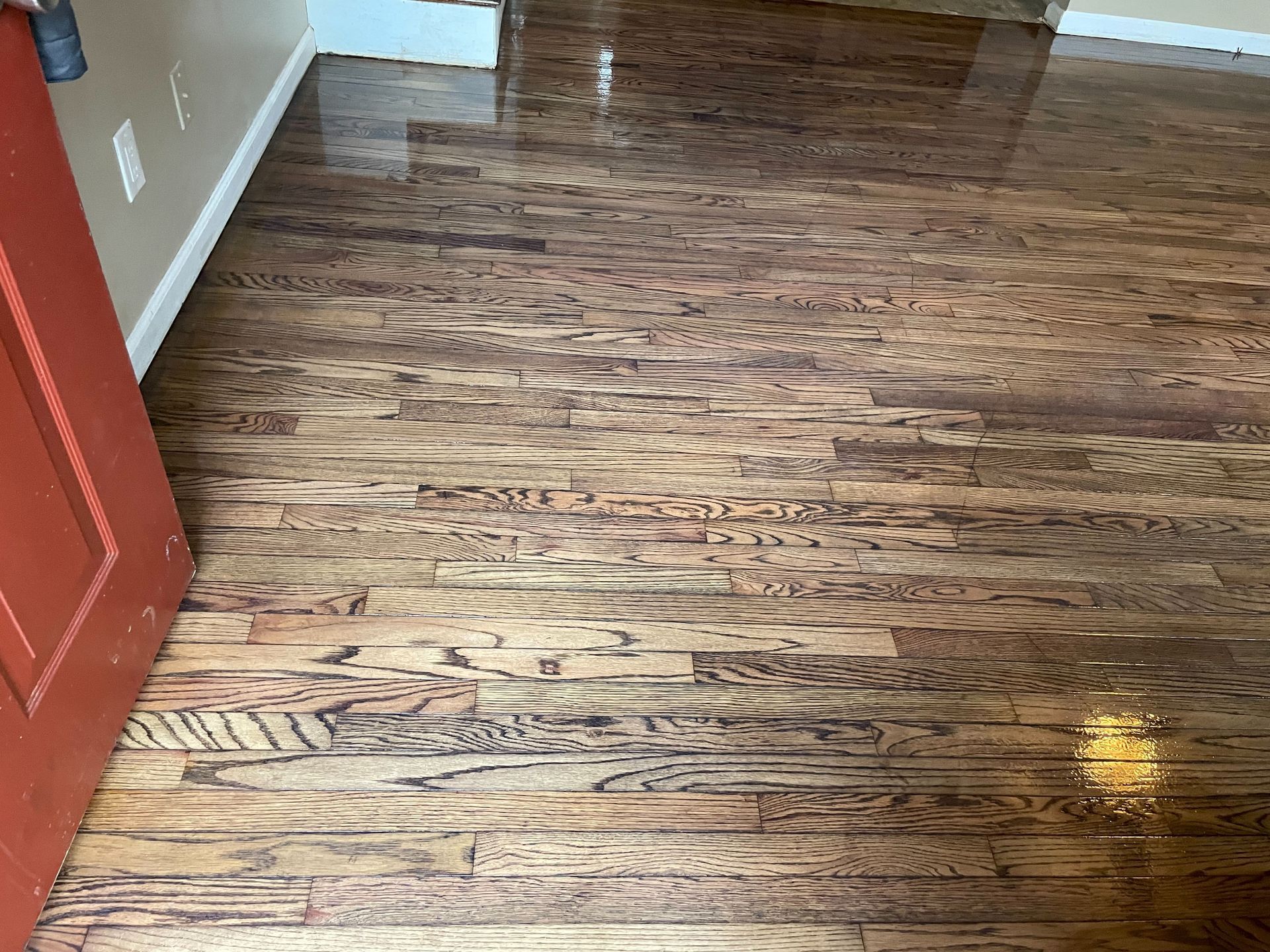 A room with a wooden floor and a red door.