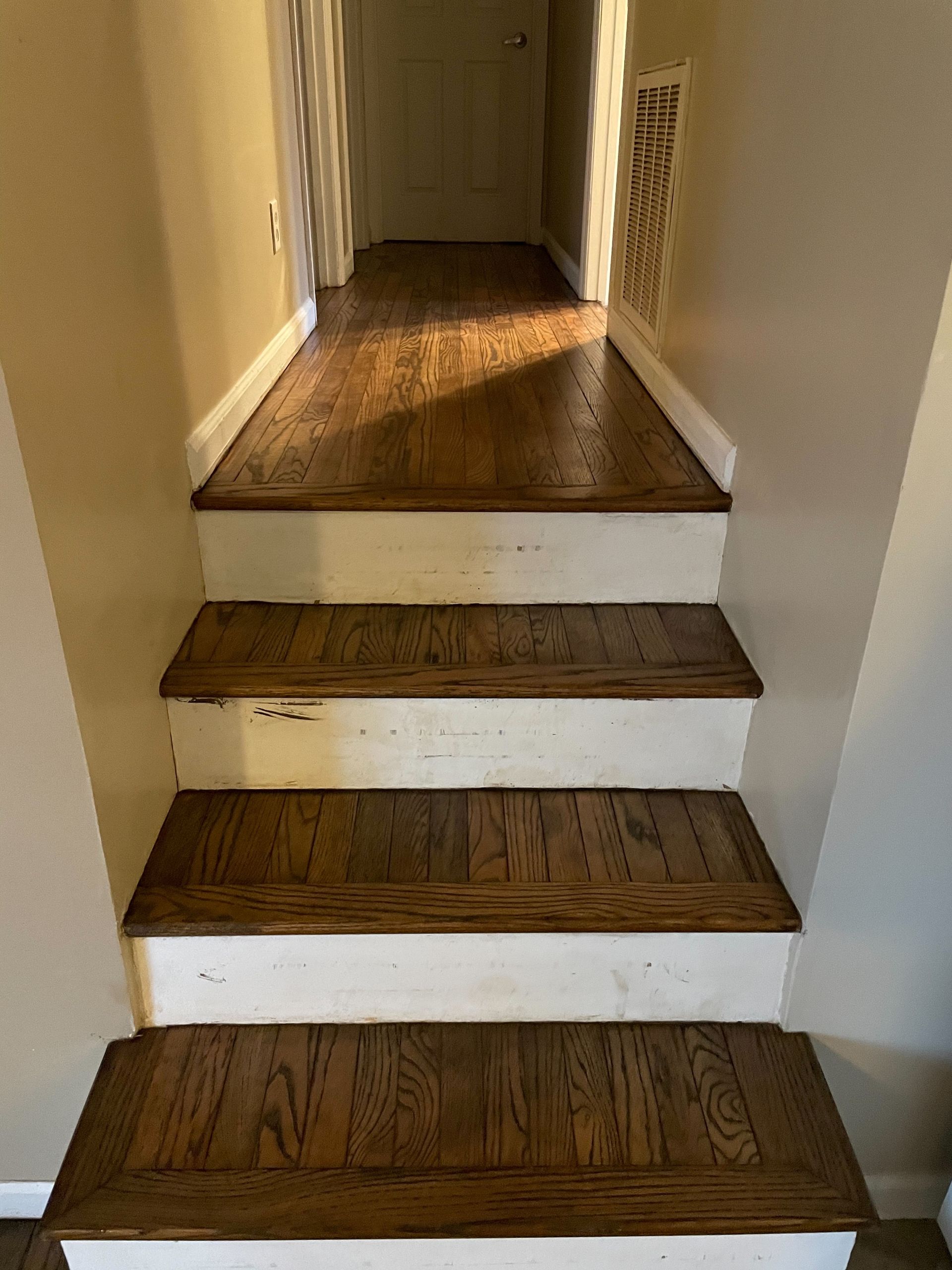 A set of wooden stairs leading up to a hallway in a house.
