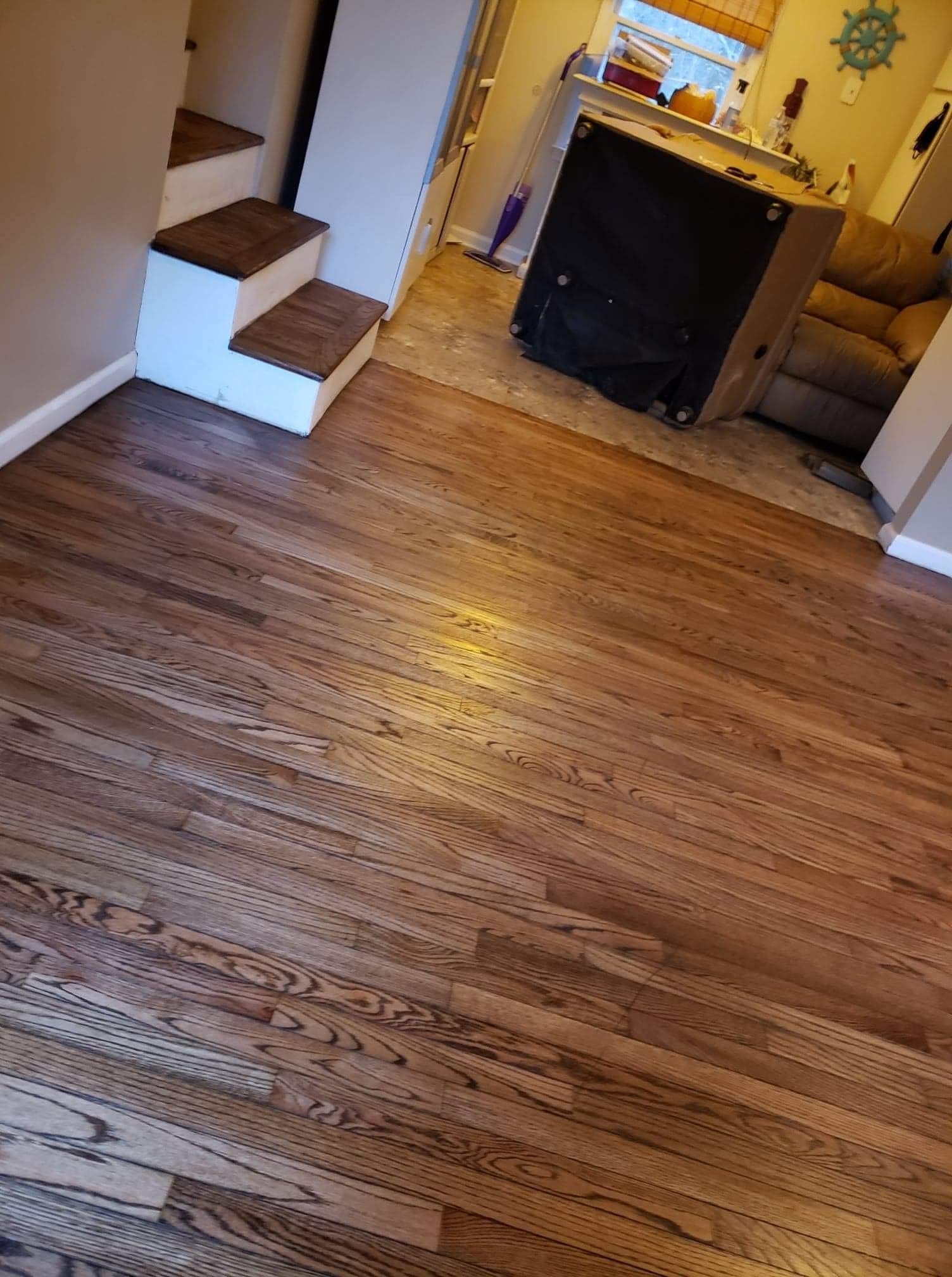 A living room with hardwood floors , stairs , a couch and a fireplace.