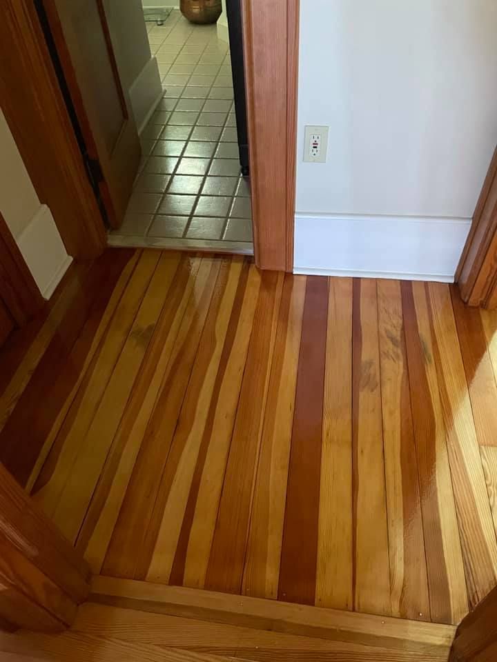 A wooden floor in a hallway next to a door.