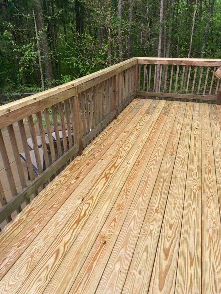 A wooden deck with a railing and trees in the background.
