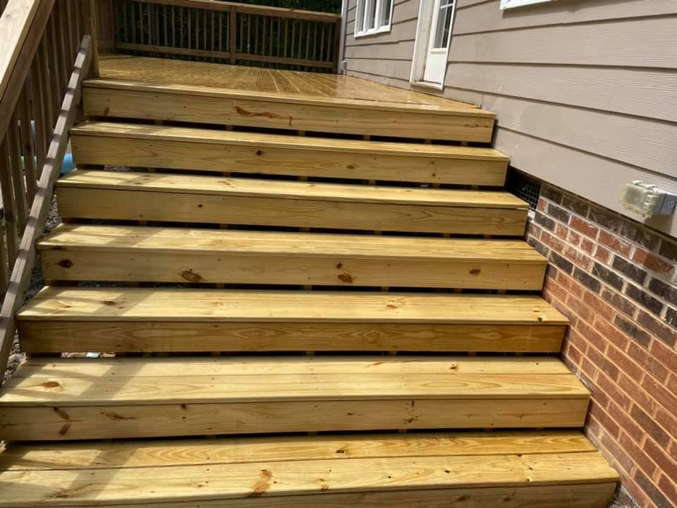 A wooden deck with stairs leading up to a brick building.