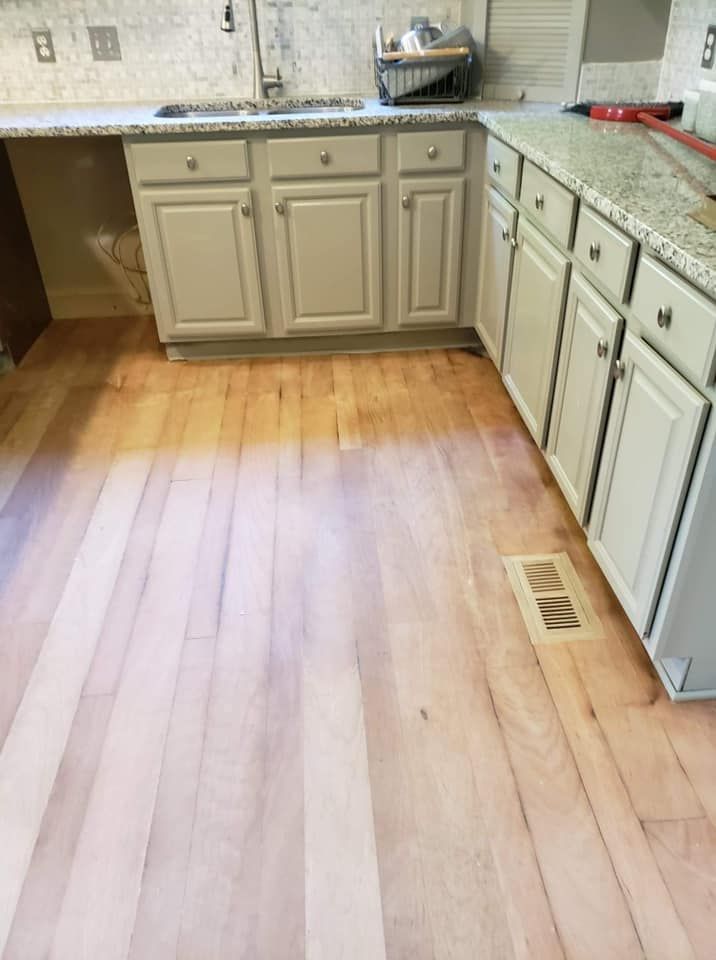 A kitchen with wooden floors and white cabinets.