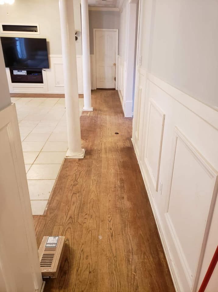 A hallway with hardwood floors and white trim in a house.