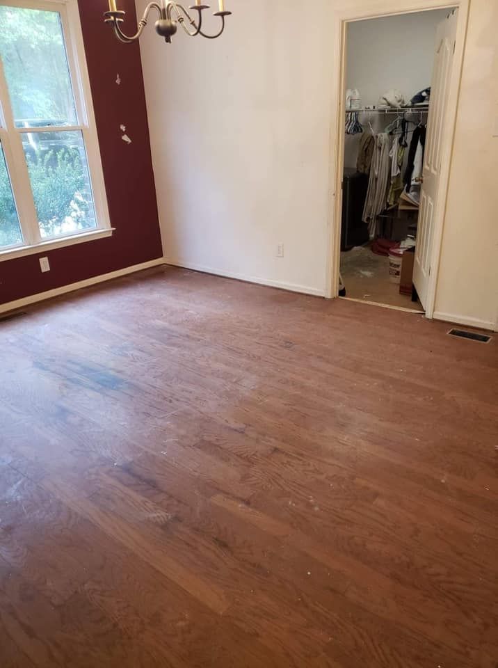 An empty room with a wooden floor and a chandelier.