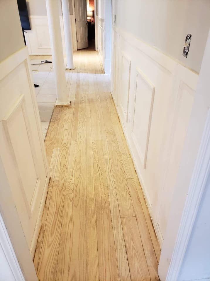 A hallway with wooden floors and white walls in a house.
