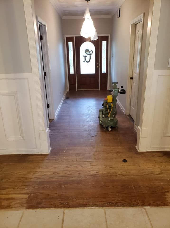 A machine is sanding a wooden floor in a hallway.
