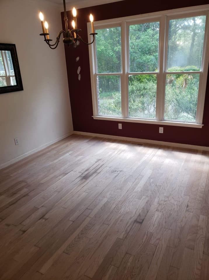 An empty room with hardwood floors and a chandelier.
