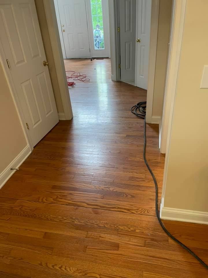 A hallway with hardwood floors and a cord hanging from the wall.