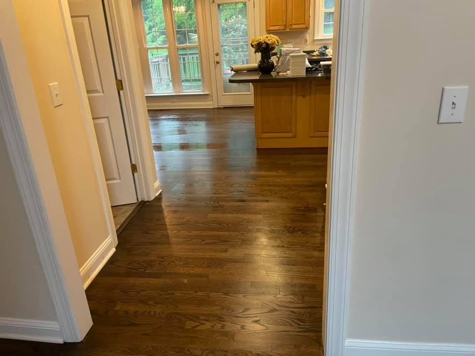A hallway leading to a kitchen with hardwood floors.
