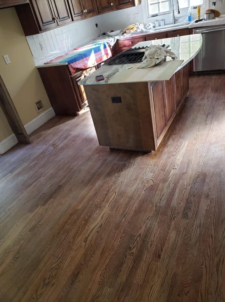 A kitchen with hardwood floors and a large island in the middle.