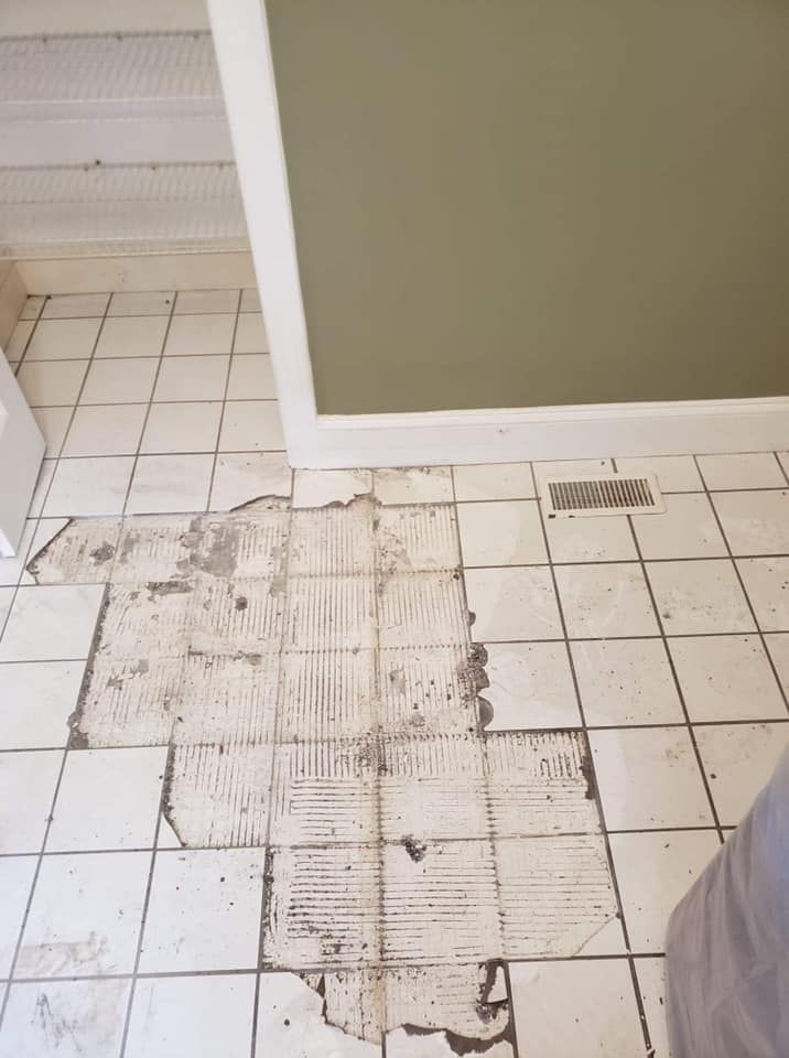 A white tile floor with a hole in it