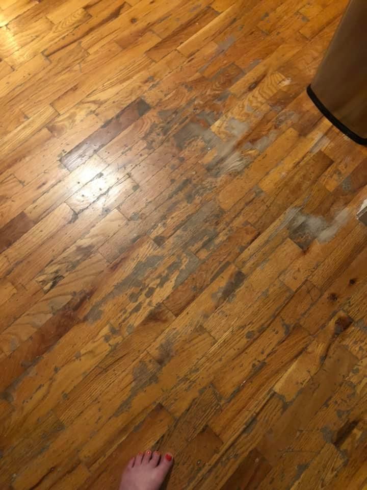 A person is standing on a wooden floor with a trash can in the background.