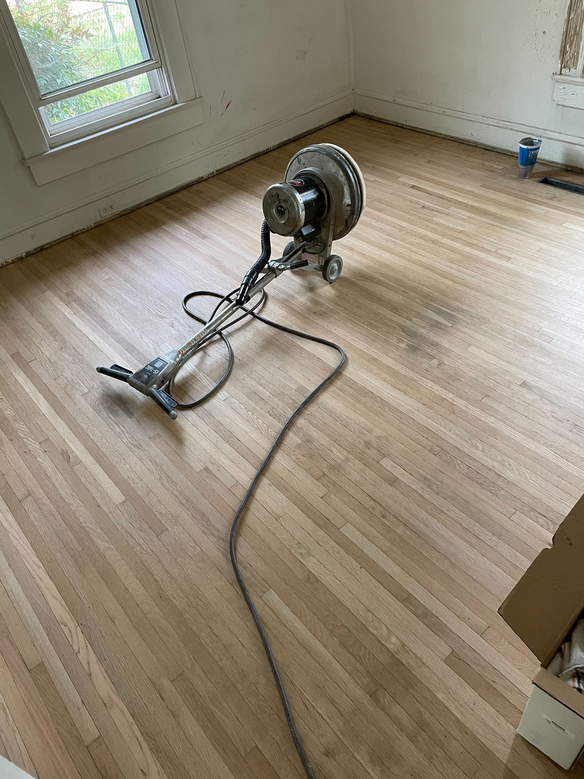 A vacuum cleaner is sitting on a wooden floor in a room.
