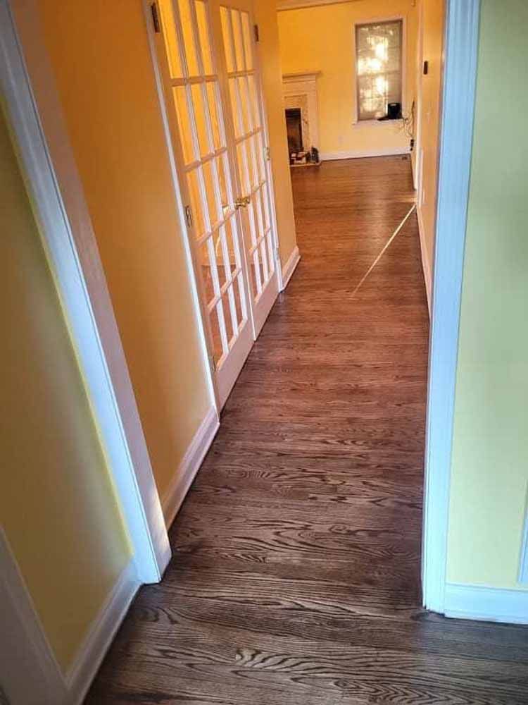 A hallway with hardwood floors and french doors leading to a living room.
