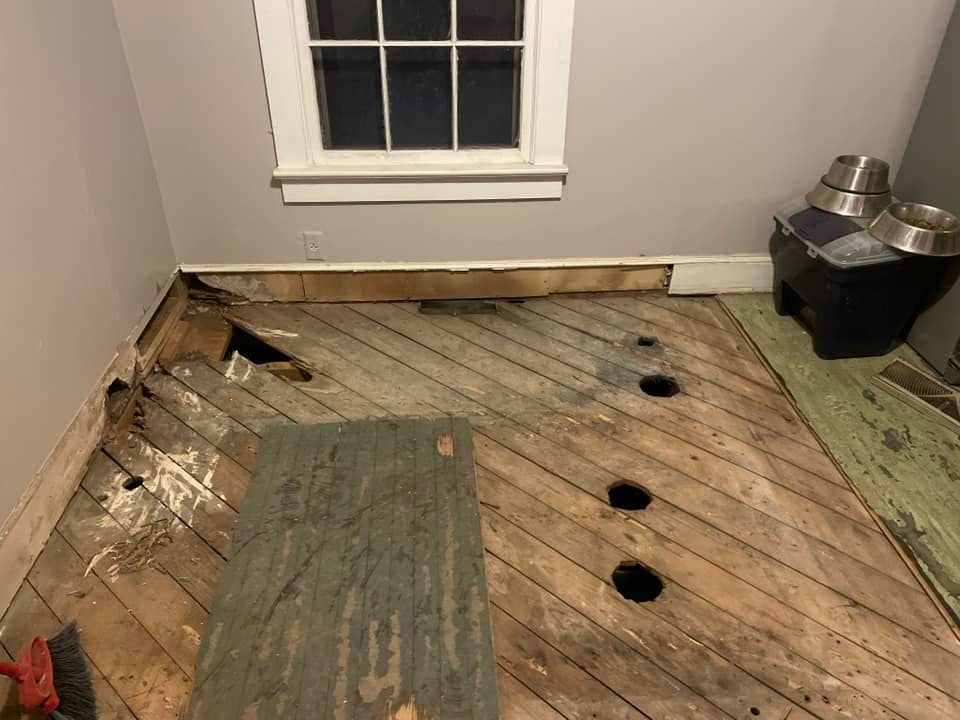 A wooden floor with holes in it and a window in the background.