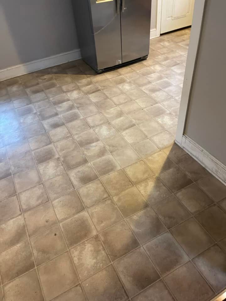 A kitchen with a tile floor and a refrigerator.