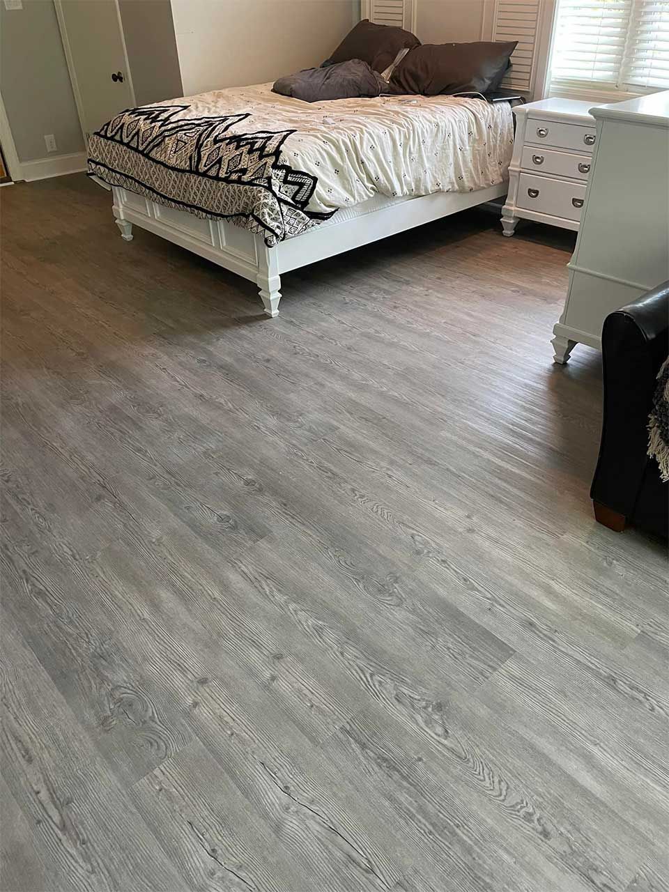 A bedroom with hardwood floors and a bed.