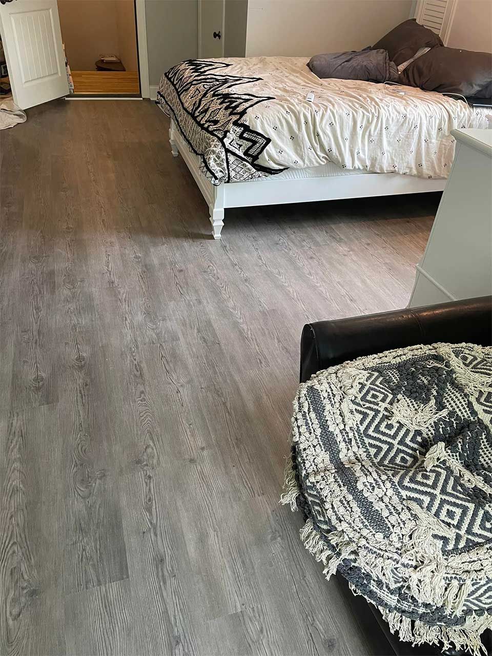 A bedroom with a bed , chair and rug on the floor.
