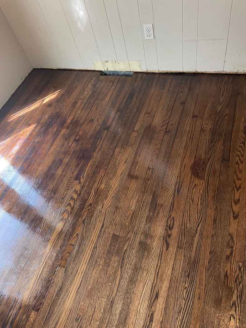 A room with a wooden floor and a white wall.