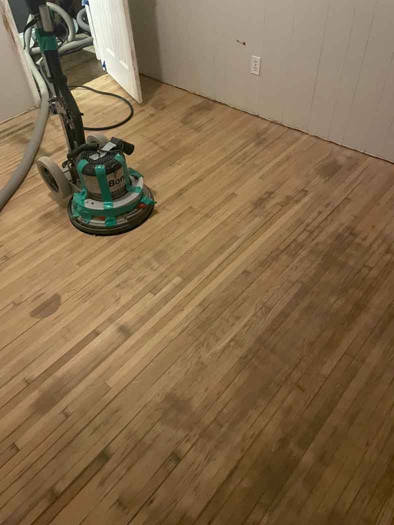 A vacuum cleaner is sitting on a wooden floor in a room.