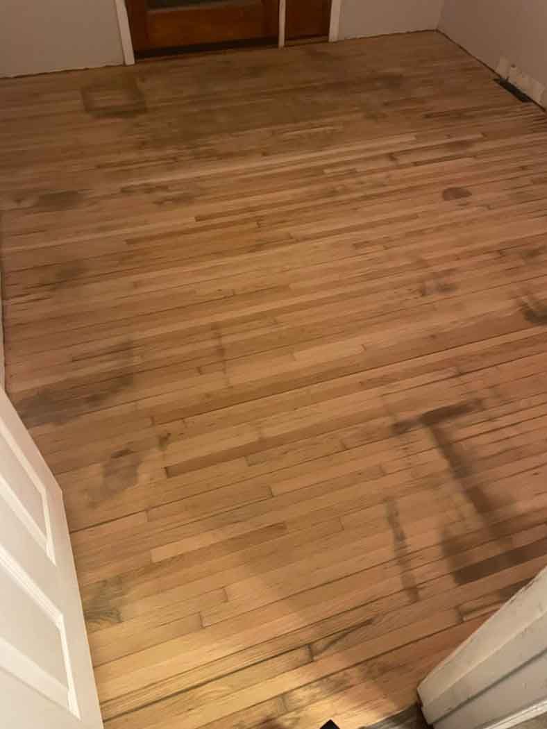 A wooden floor in a room next to a door.