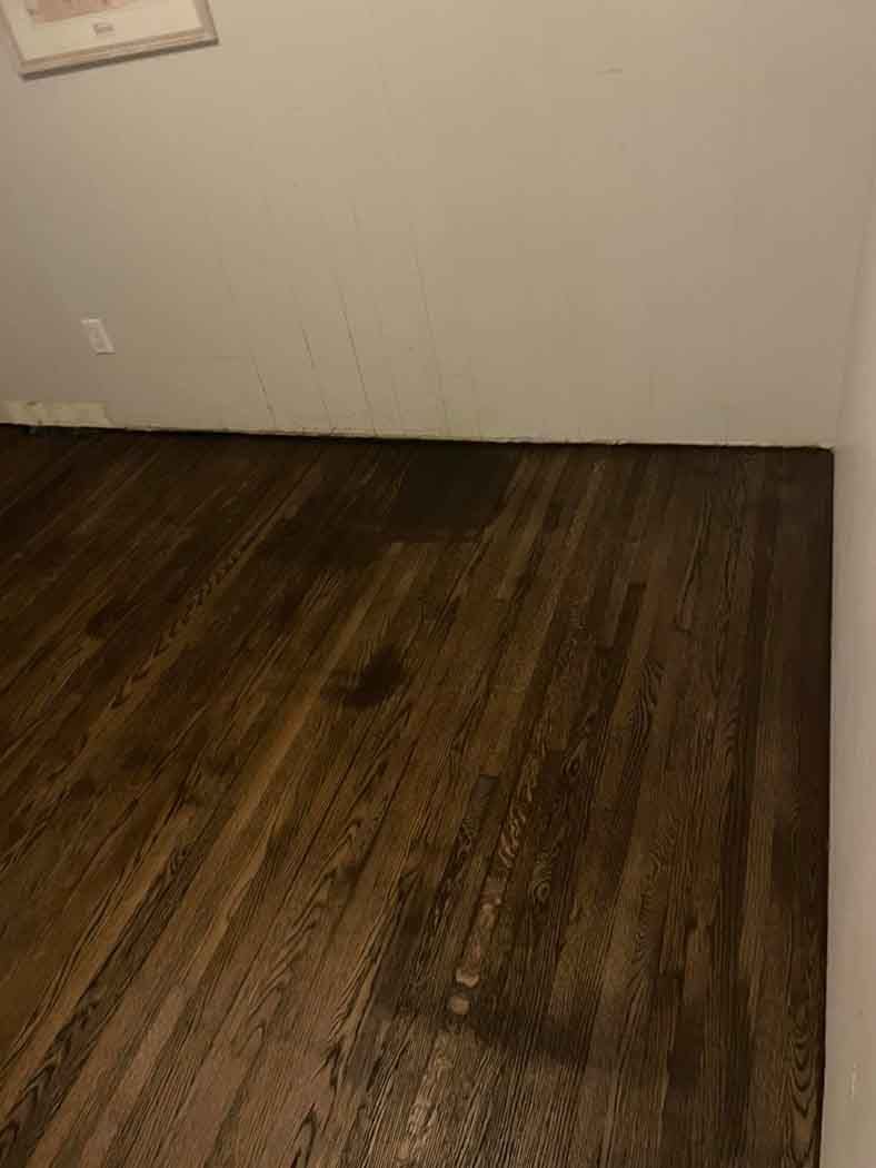 A room with a wooden floor and a white wall.