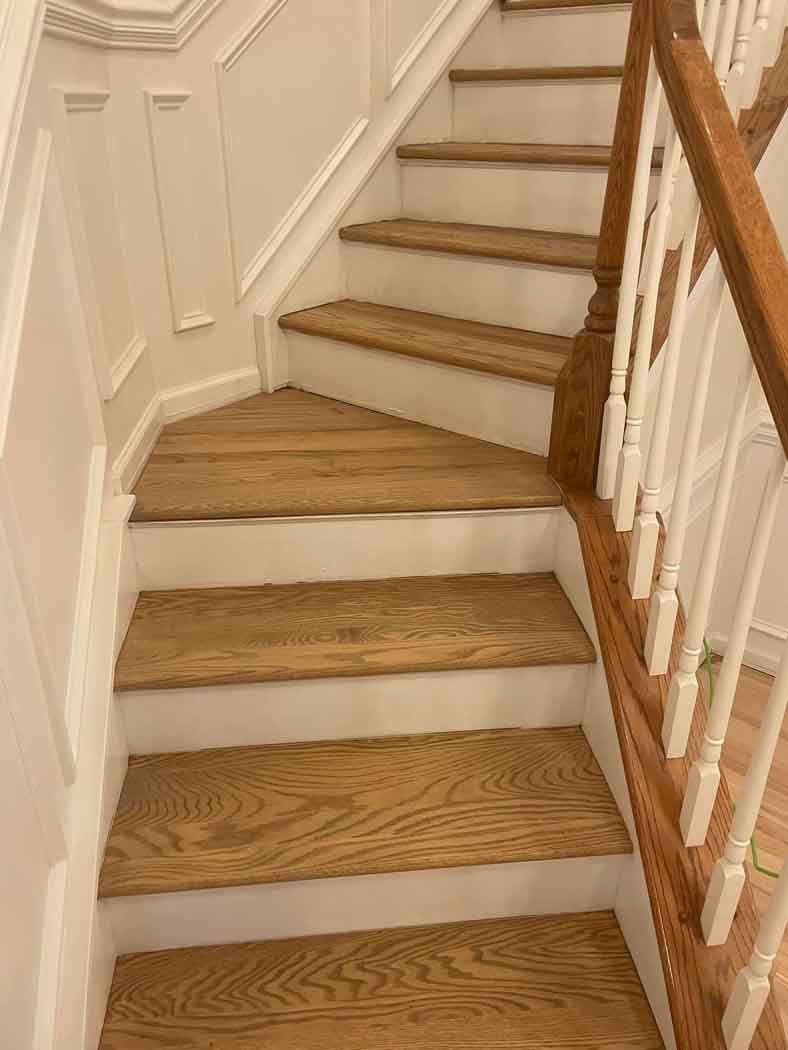 A wooden staircase with white steps and a wooden railing.