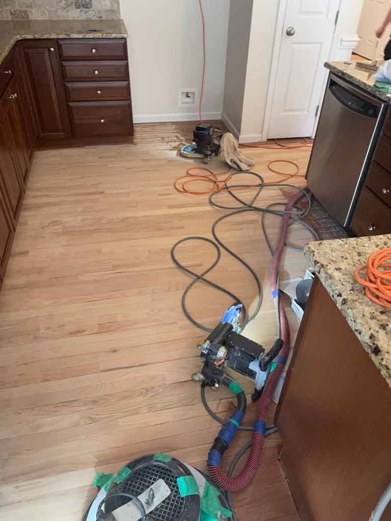 A kitchen with a wooden floor and a vacuum cleaner on the floor.