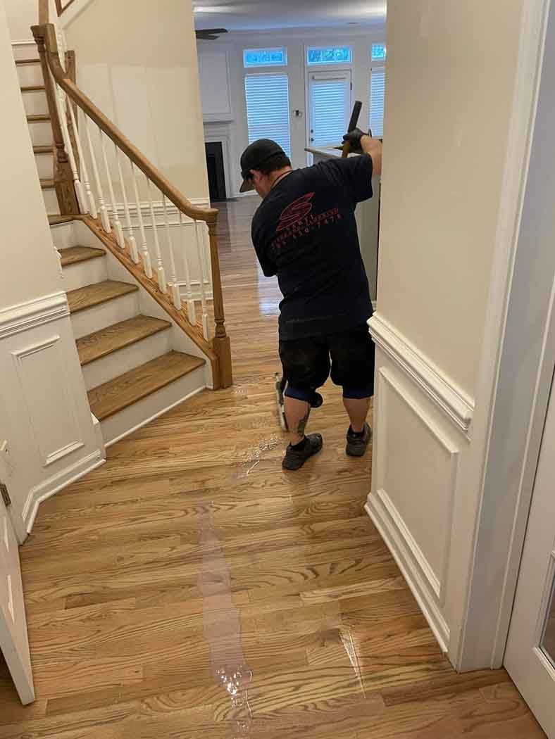 A man is standing in a hallway next to a staircase.