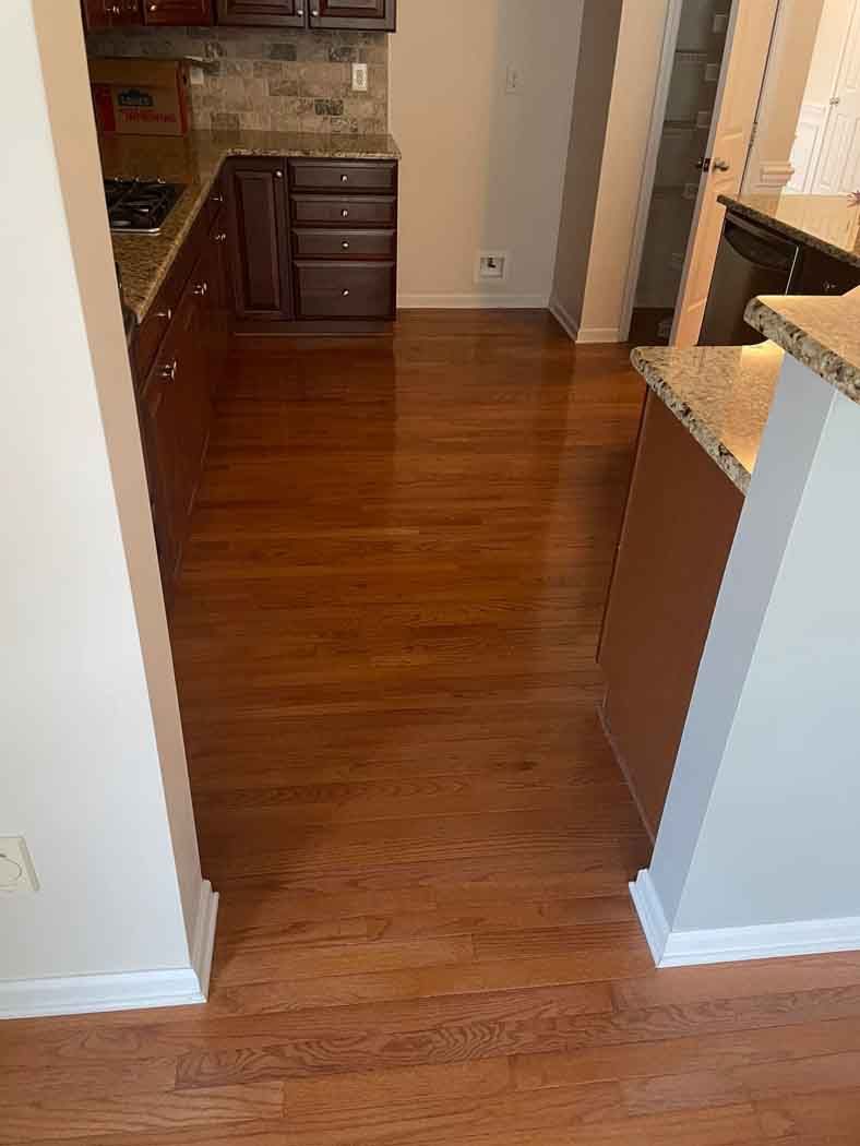 A kitchen with hardwood floors and cabinets in a house.