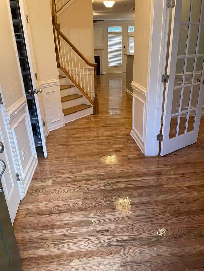 A hallway with hardwood floors and stairs in a house.