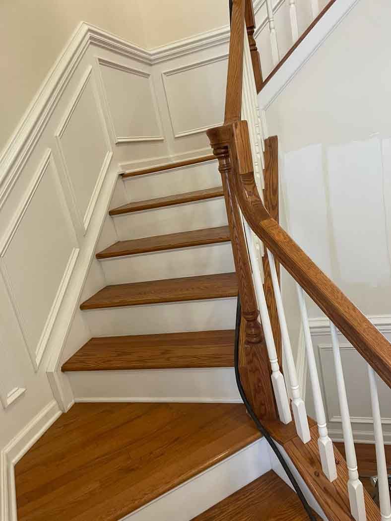 A staircase with wooden steps and white railing in a house.