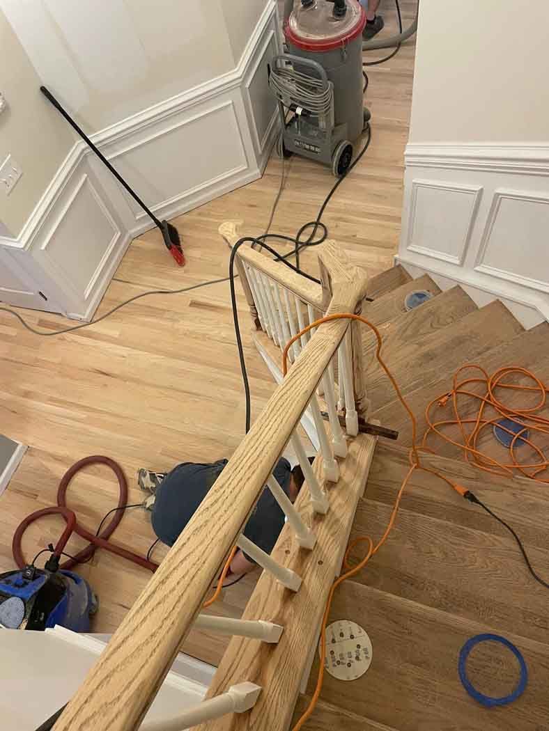 A wooden railing is being installed on a wooden staircase.