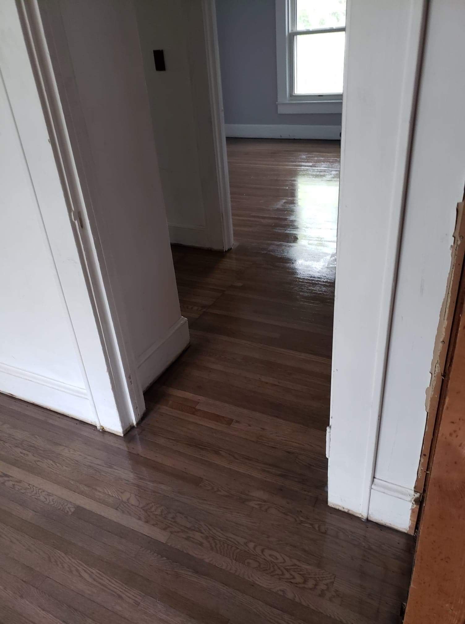 A hallway with hardwood floors and white walls in a house.