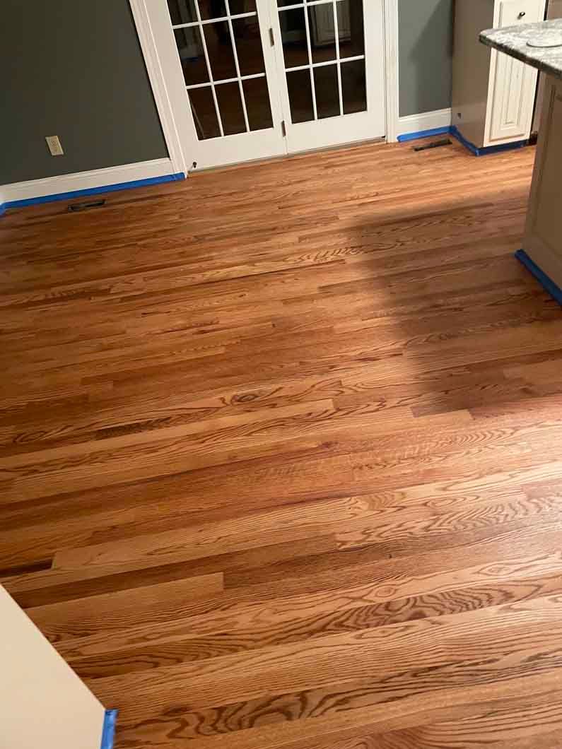 A kitchen with a wooden floor and french doors.
