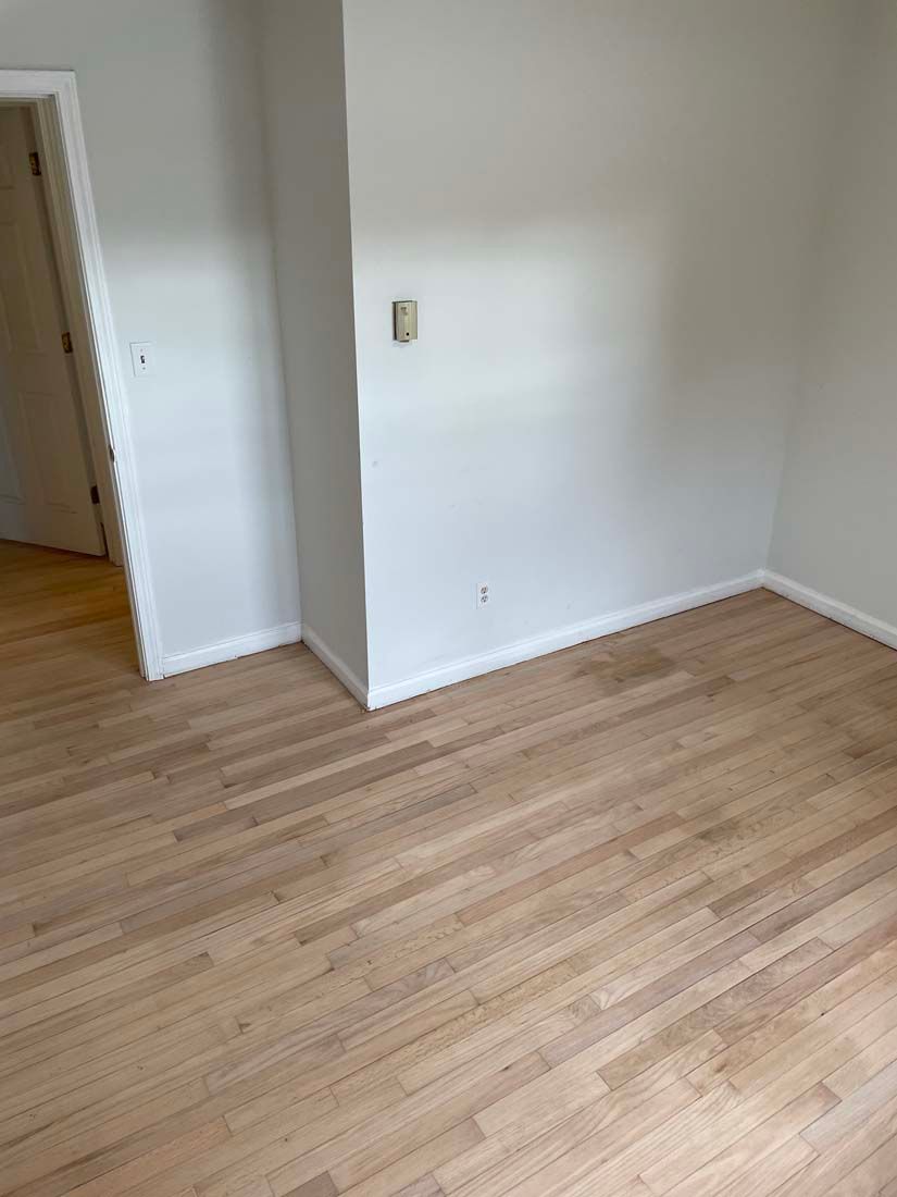 An empty room with hardwood floors and white walls.