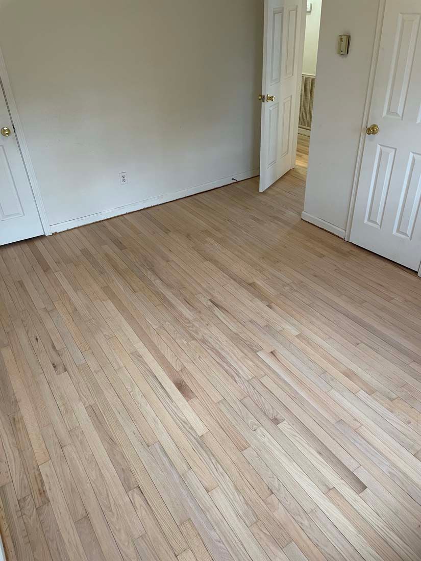A bedroom with hardwood floors and white walls.