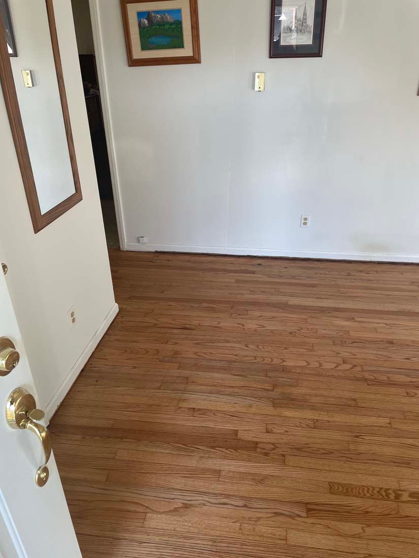 A room with hardwood floors and a mirror on the wall.