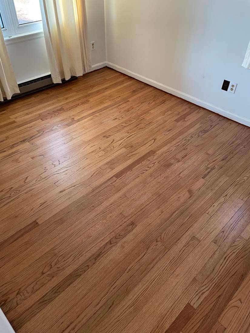 A bedroom with hardwood floors and white walls.
