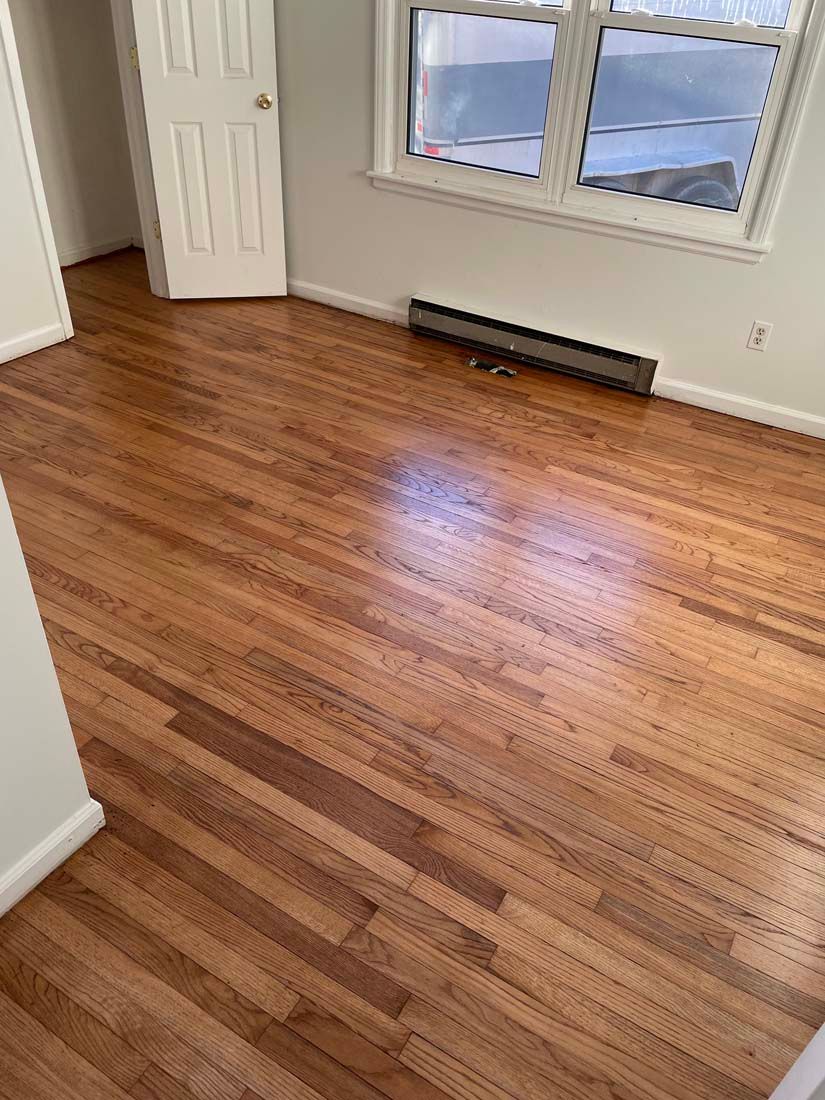 An empty room with hardwood floors and a window.