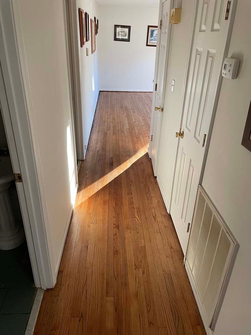 A hallway with hardwood floors and white doors in a house.