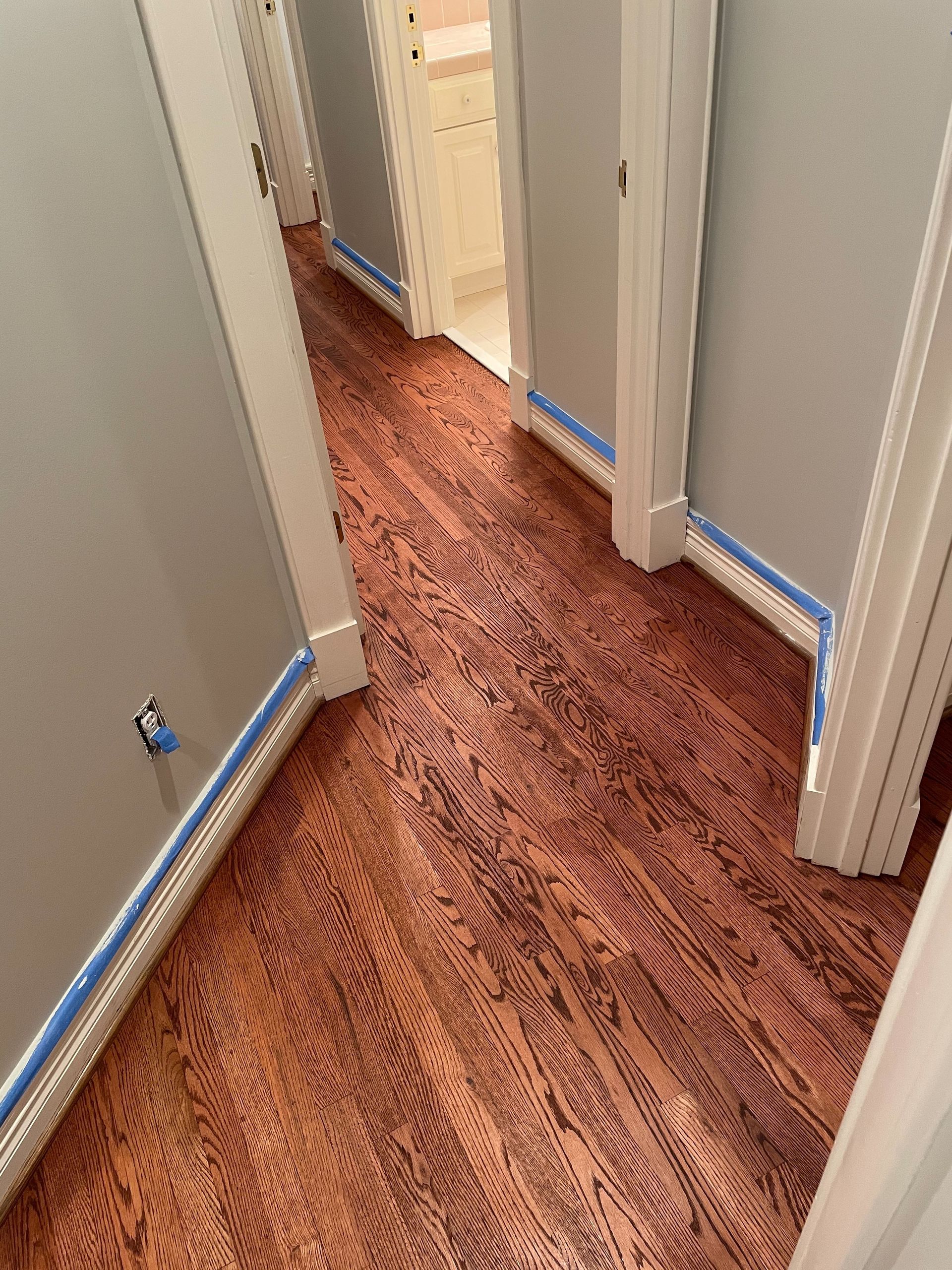 A hallway with hardwood floors and gray walls.