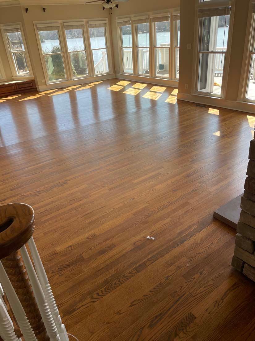 An empty living room with hardwood floors and lots of windows.