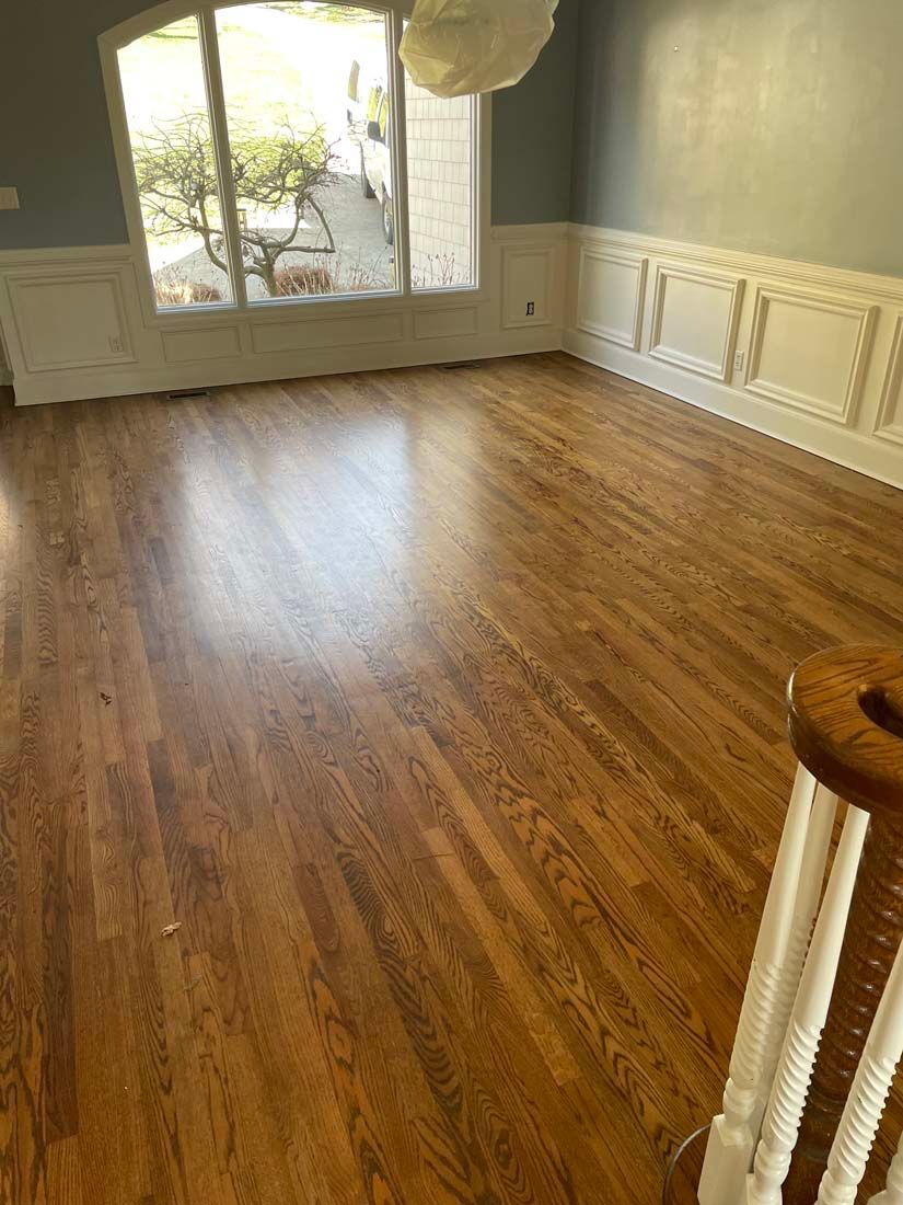 An empty living room with hardwood floors and a staircase.
